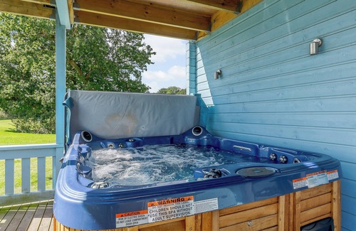 Hopton Cottage | Relax in the hot tub whilst enjoying open views over the golf course and lakes.