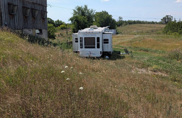 Serenity Lane Farm Stay: a trailer next to a barn full of farm animals
